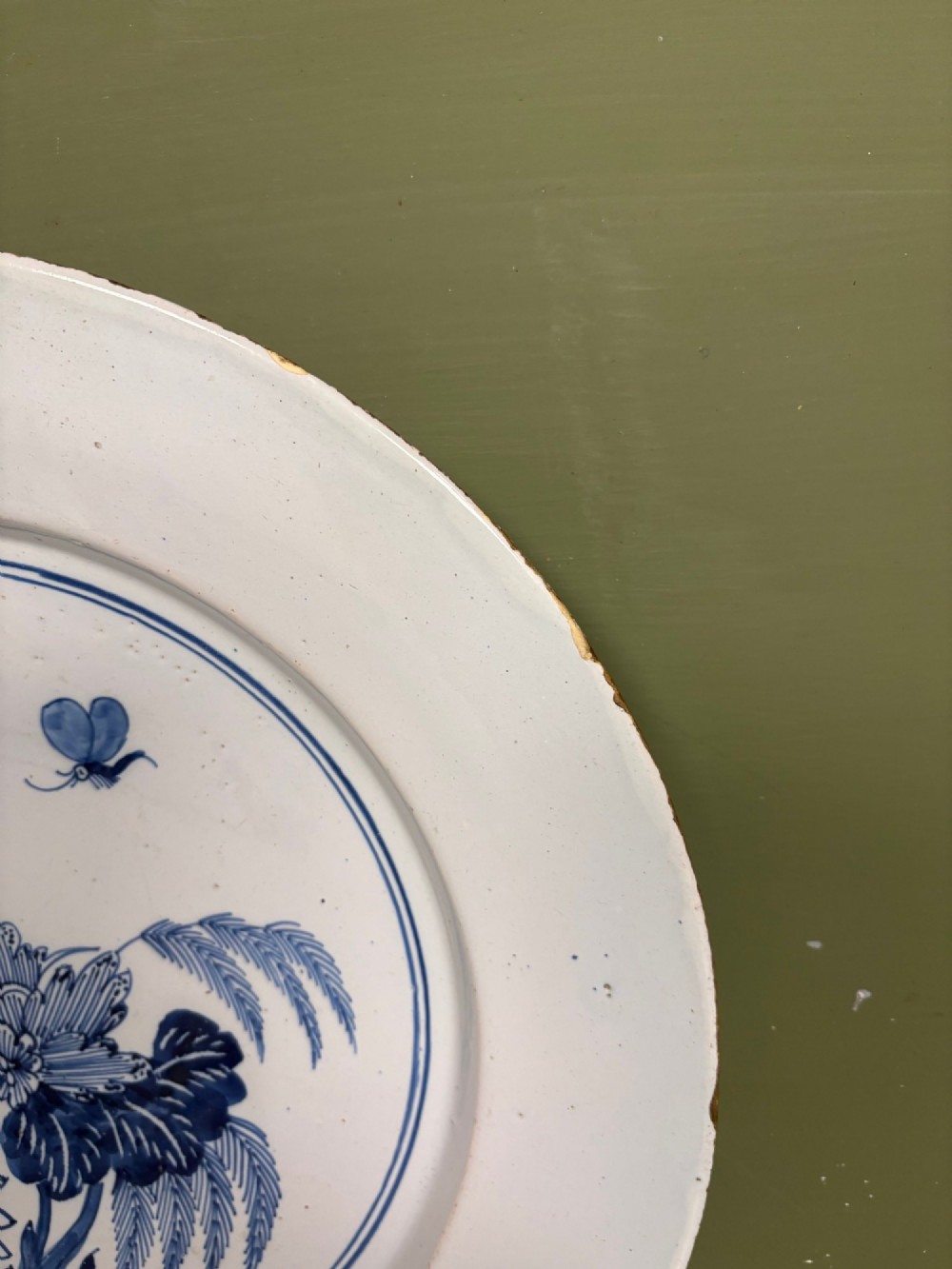 An 18th-century circular blue and white tin-glazed earthenware charger featuring a central hand-painted floral motif with a butterfly detail. View II