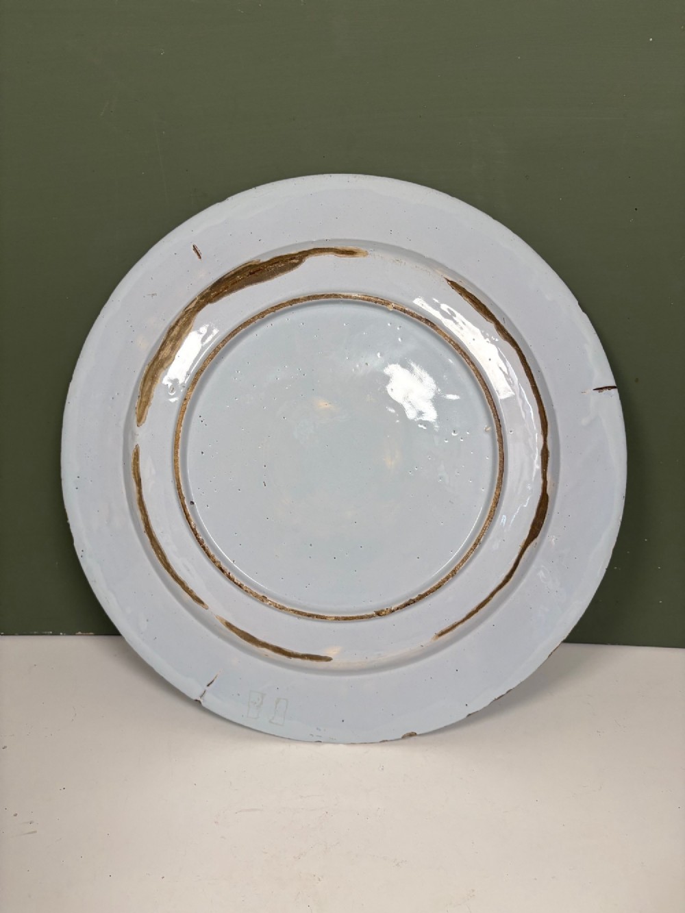 An 18th-century circular blue and white tin-glazed earthenware charger featuring a central hand-painted floral motif with a butterfly detail. View III