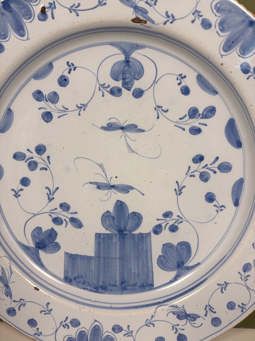 An 18th-century circular blue and white Delftware charger decorated with hand-painted floral and insect motifs. View II
