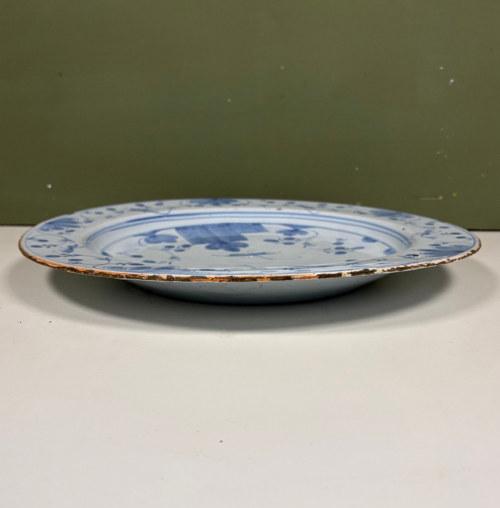 An 18th-century circular blue and white Delftware charger decorated with hand-painted floral and insect motifs. View VI