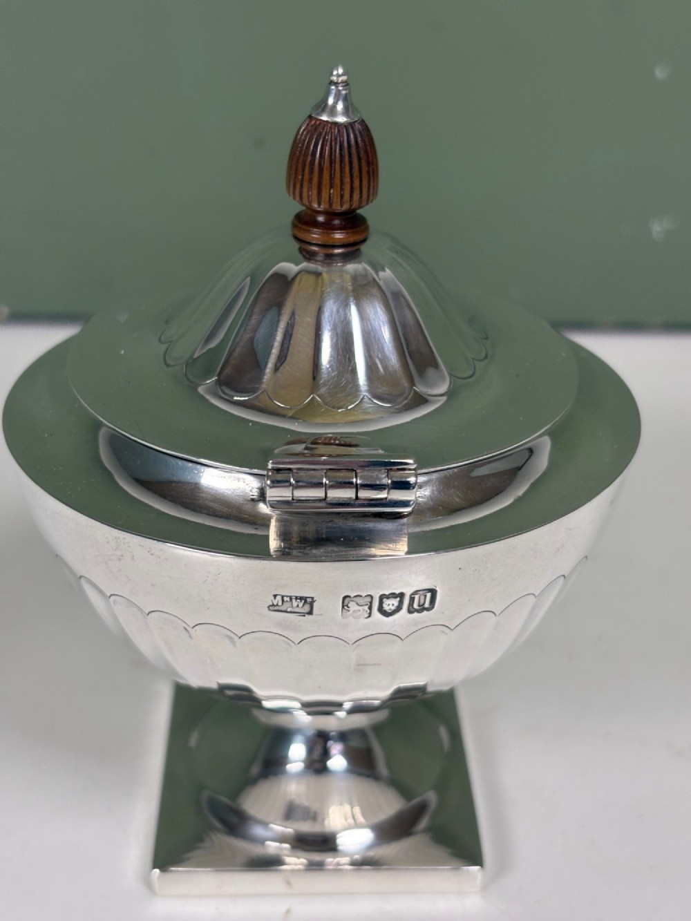 A silver fluted tea caddy with a stepped square base, domed cover, and turned wooden finial. View III