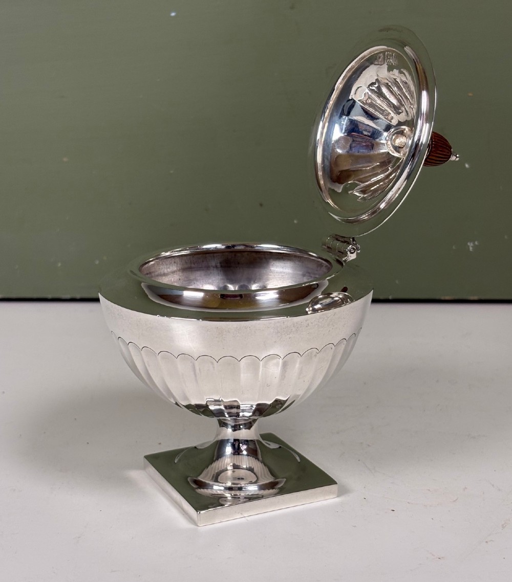 A silver fluted tea caddy with a stepped square base, domed cover, and turned wooden finial. View IV