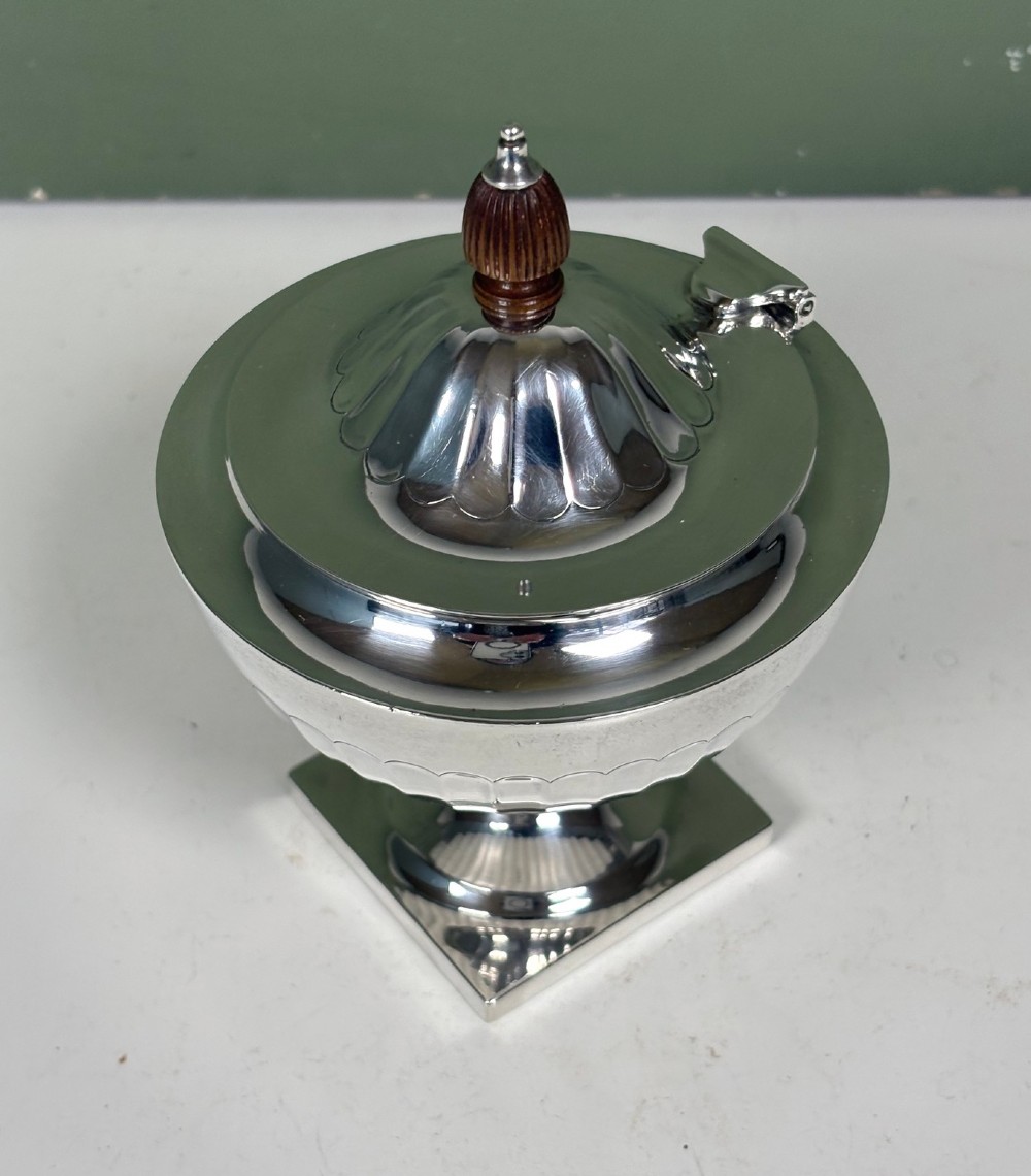 A silver fluted tea caddy with a stepped square base, domed cover, and turned wooden finial. View V