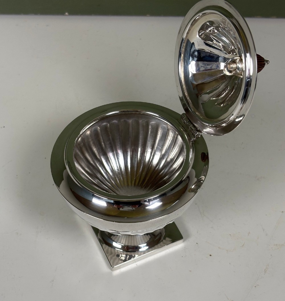 A silver fluted tea caddy with a stepped square base, domed cover, and turned wooden finial. View VI