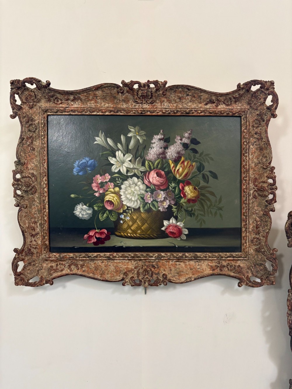 A pair of 19th-century oil paintings displaying botanical floral arrangements in woven baskets within ornate swept gilt frames. View II