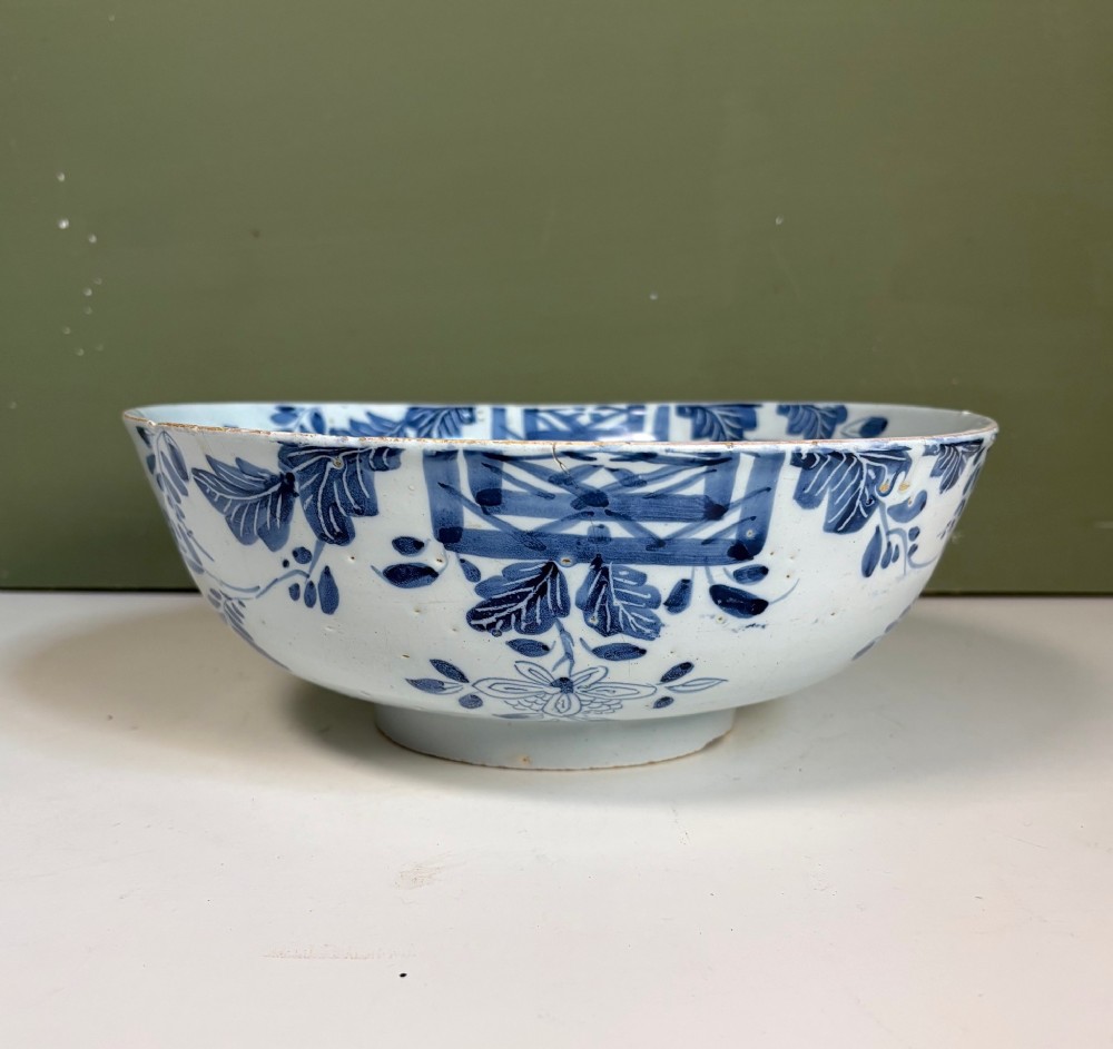 An 18th-century blue and white tin-glazed earthenware bowl with hand-painted cobalt blue botanical decoration.