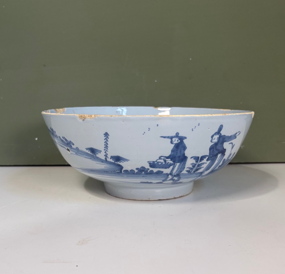 An 18th-century tin-glazed earthenware bowl decorated with hand-painted cobalt blue figurative scenes on a footed base.