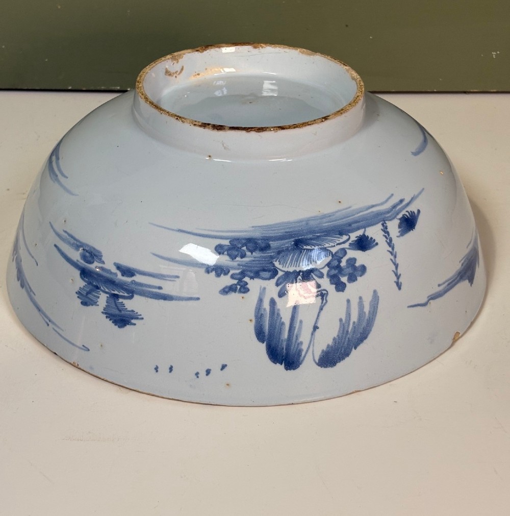 An 18th-century tin-glazed earthenware bowl decorated with hand-painted cobalt blue figurative scenes on a footed base. View V