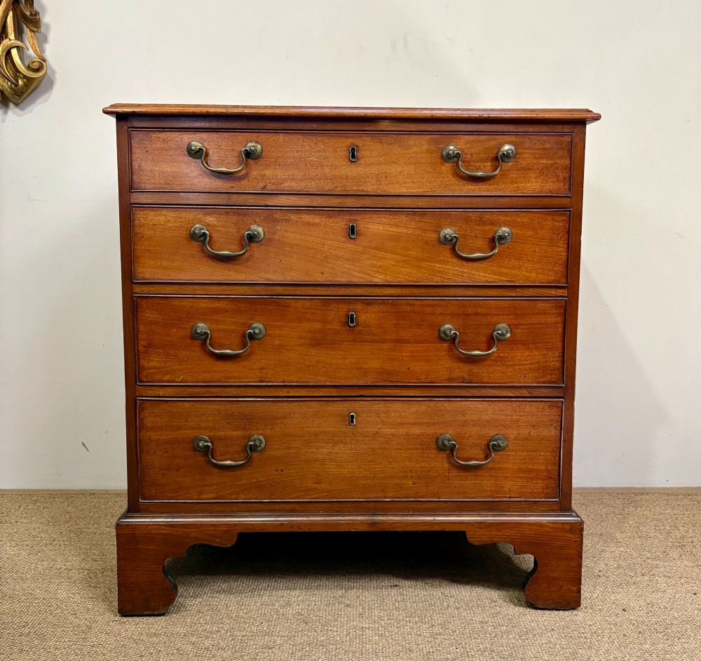 A George III mahogany chest of four graduated drawers with brass swan-neck handles and bracket feet.