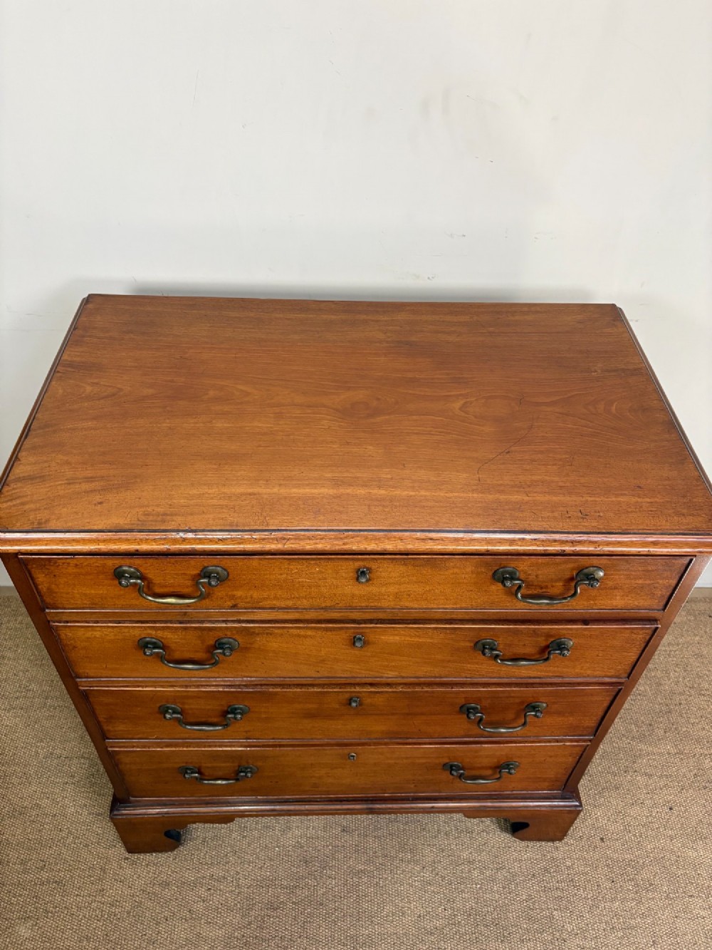 A George III mahogany chest of four graduated drawers with brass swan-neck handles and bracket feet. View II