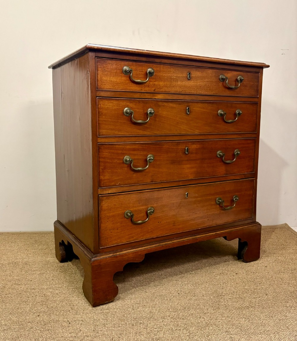 A George III mahogany chest of four graduated drawers with brass swan-neck handles and bracket feet. View III