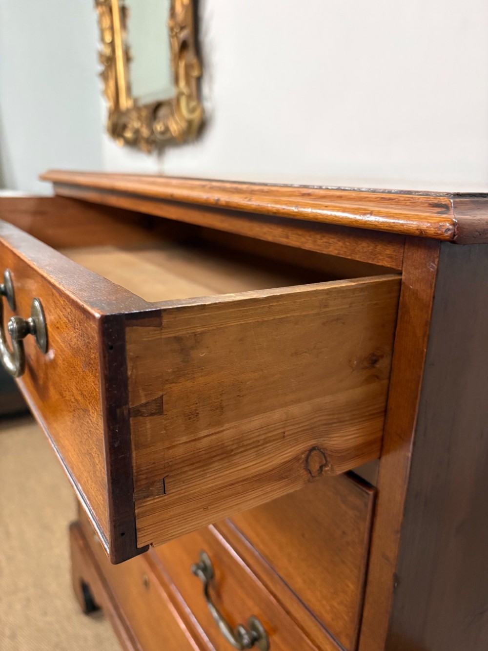 A George III mahogany chest of four graduated drawers with brass swan-neck handles and bracket feet. View VI