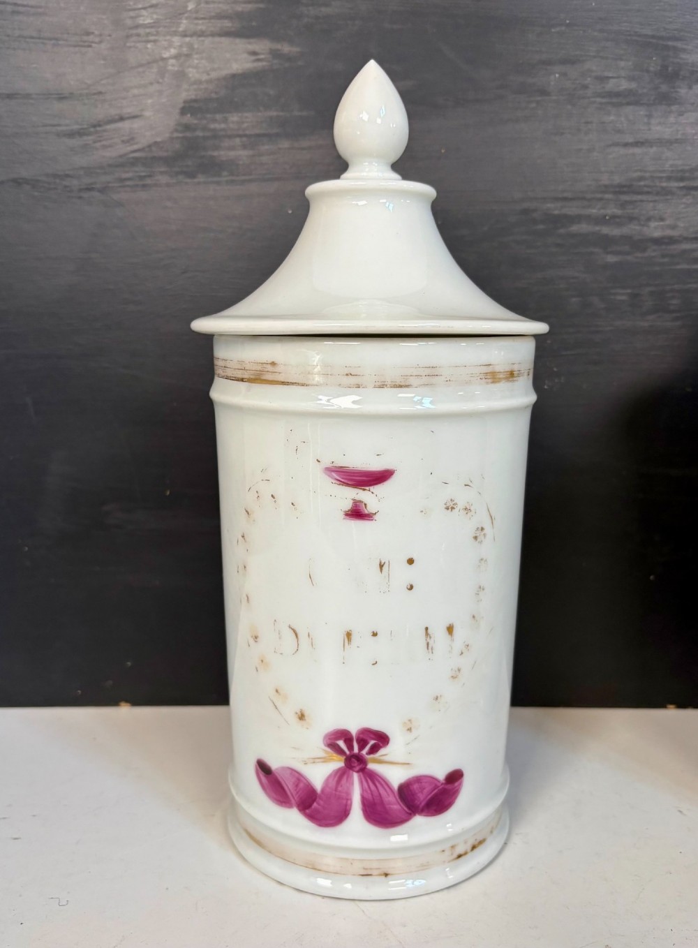 Set of five matching off-white 19th-century porcelain apothecary jars featuring pointed finial lids and hand-painted magenta bow motifs. View V