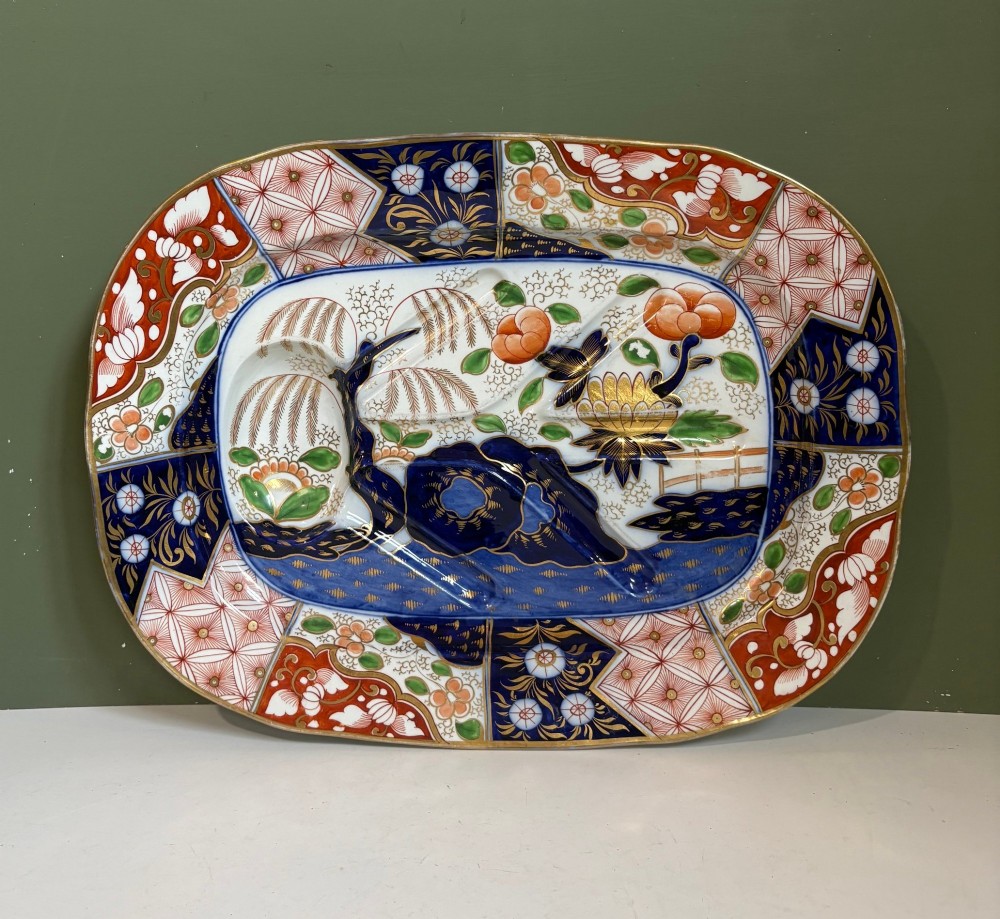 A large oval 19th-century Coalport porcelain meat platter featuring an Imari pattern with cobalt blue, iron red, and gold leaf detailing around a moulded tree-and-well channel.