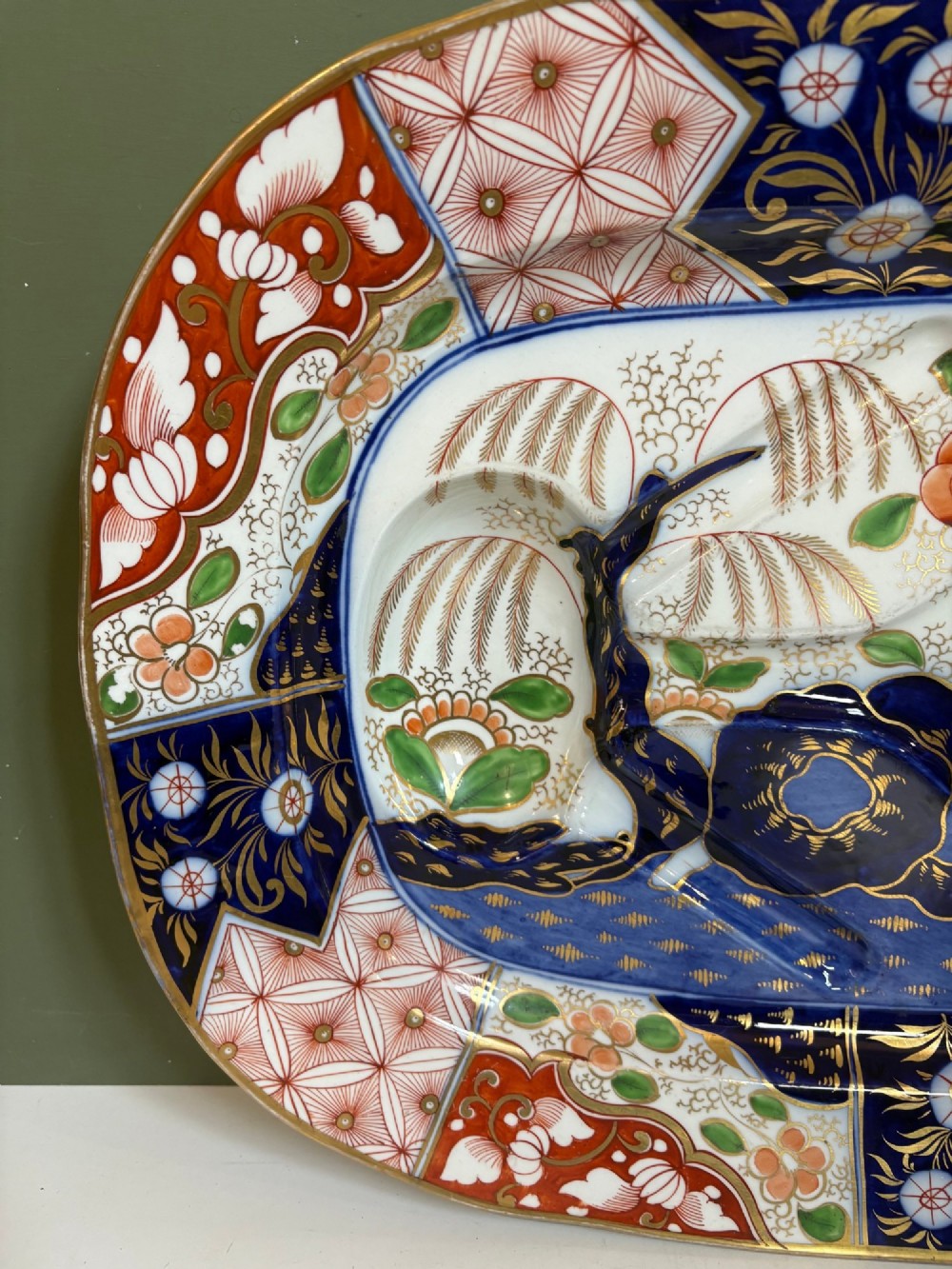 A large oval 19th-century Coalport porcelain meat platter featuring an Imari pattern with cobalt blue, iron red, and gold leaf detailing around a moulded tree-and-well channel. View III