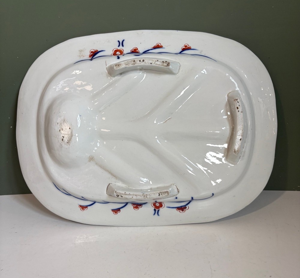 A large oval 19th-century Coalport porcelain meat platter featuring an Imari pattern with cobalt blue, iron red, and gold leaf detailing around a moulded tree-and-well channel. View V