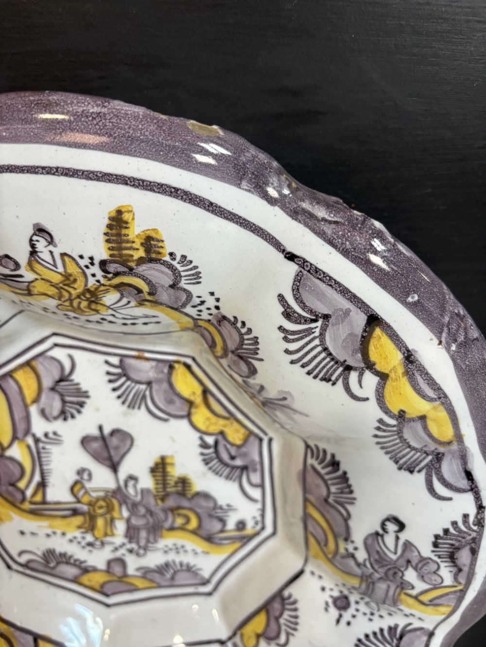 A pair of circular 18th-century tin-glazed earthenware dishes featuring hand-painted manganese purple and yellow chinoiserie figures surrounded by scalloped edges. View IV