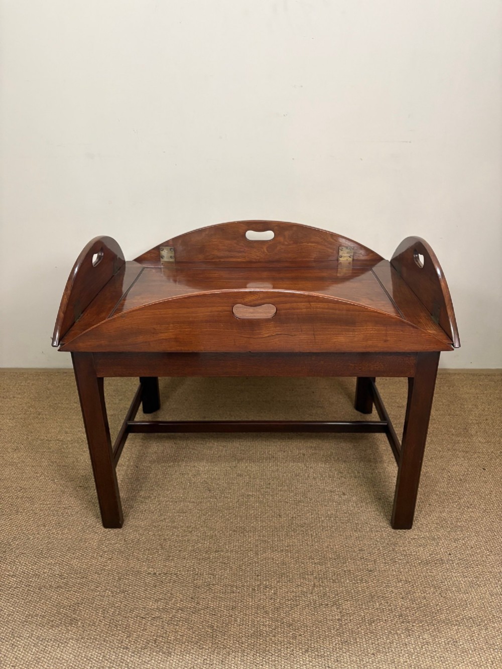 A Georgian mahogany butlers tray with hinged drop sides and cutout handles, resting on a matching wooden table base. View III