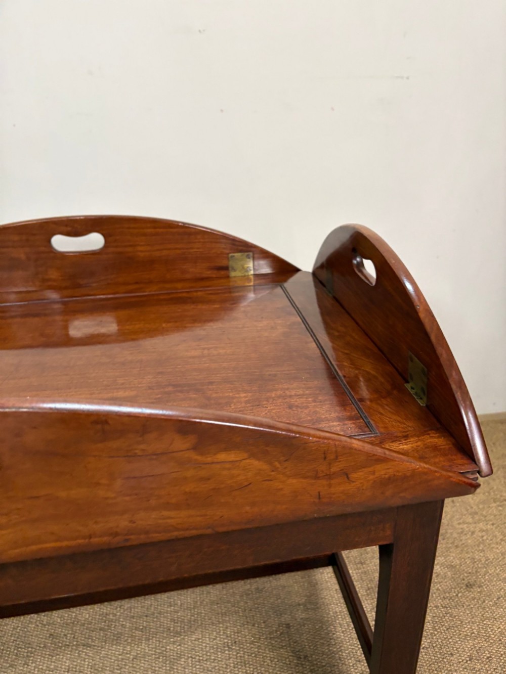 A Georgian mahogany butlers tray with hinged drop sides and cutout handles, resting on a matching wooden table base. View V