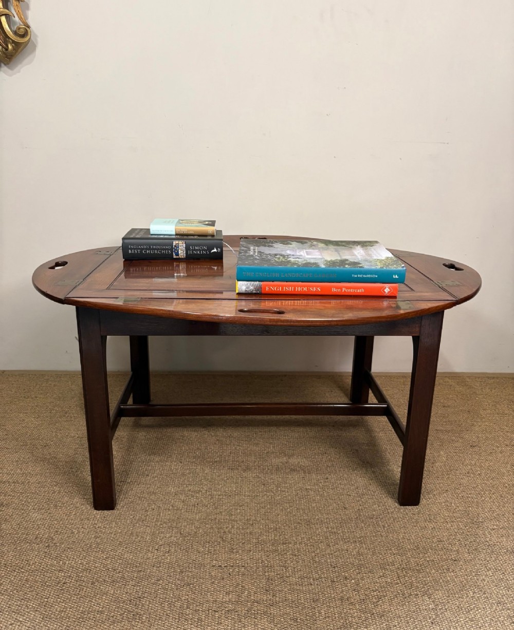 A Georgian mahogany butlers tray with hinged drop sides and cutout handles, resting on a matching wooden table base. View VI