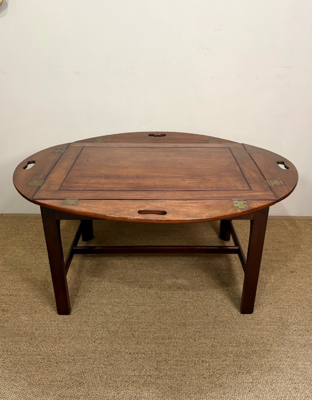 A Georgian mahogany butlers tray with hinged drop sides and cutout handles, resting on a matching wooden table base. View VII