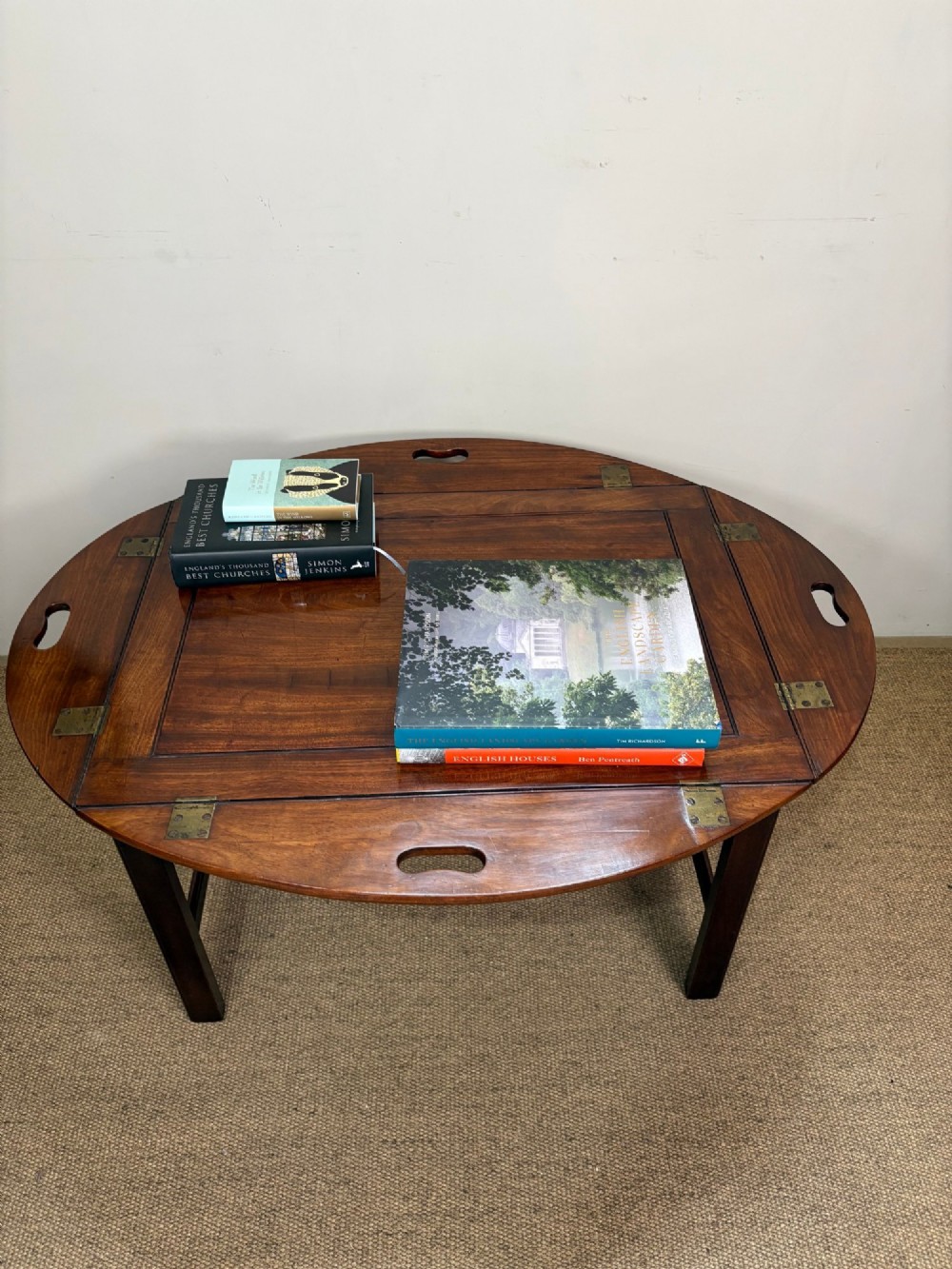 A Georgian mahogany butlers tray with hinged drop sides and cutout handles, resting on a matching wooden table base. View VIII
