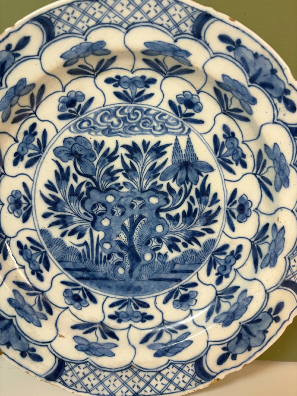 A circular 18th-century tin-glazed earthenware dish decorated with hand-painted cobalt blue floral motifs and geometric diaper borders on a white ground. View II