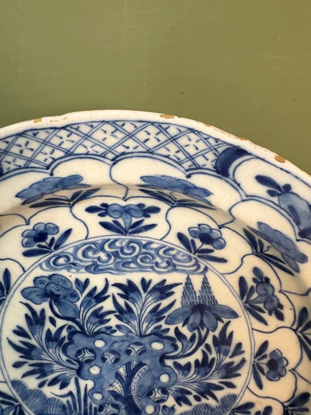 A circular 18th-century tin-glazed earthenware dish decorated with hand-painted cobalt blue floral motifs and geometric diaper borders on a white ground. View III