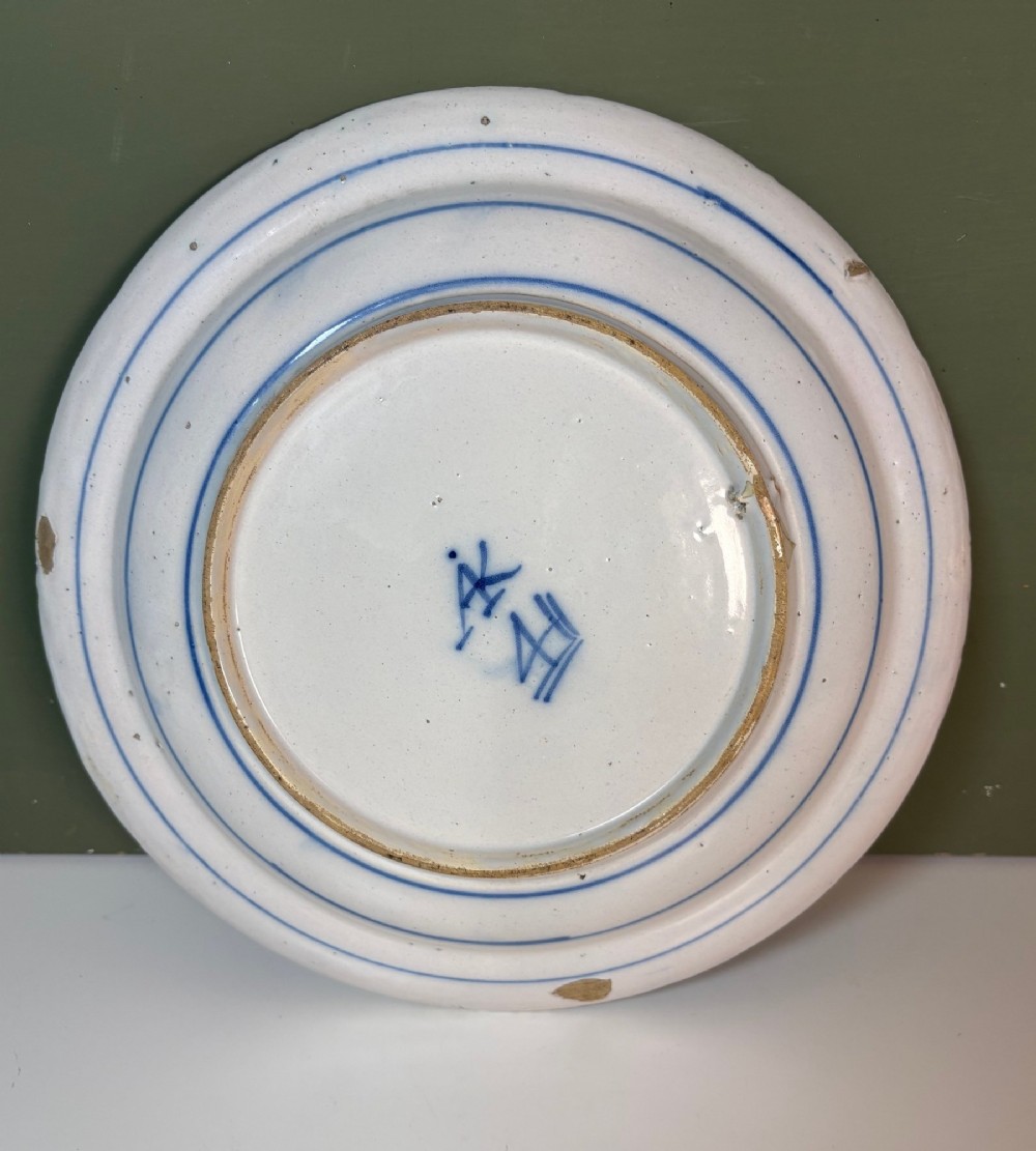 A circular 18th-century tin-glazed earthenware dish decorated with hand-painted cobalt blue floral motifs and geometric diaper borders on a white ground. View IV
