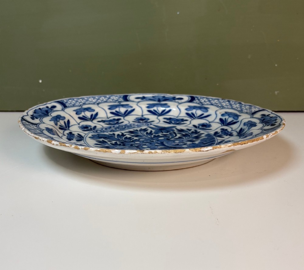 A circular 18th-century tin-glazed earthenware dish decorated with hand-painted cobalt blue floral motifs and geometric diaper borders on a white ground. View V