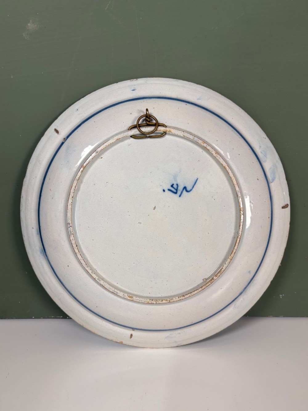 A circular 18th-century tin-glazed earthenware dish decorated in cobalt blue and white with a central Chinoiserie figure surrounded by floral border panels. View IV