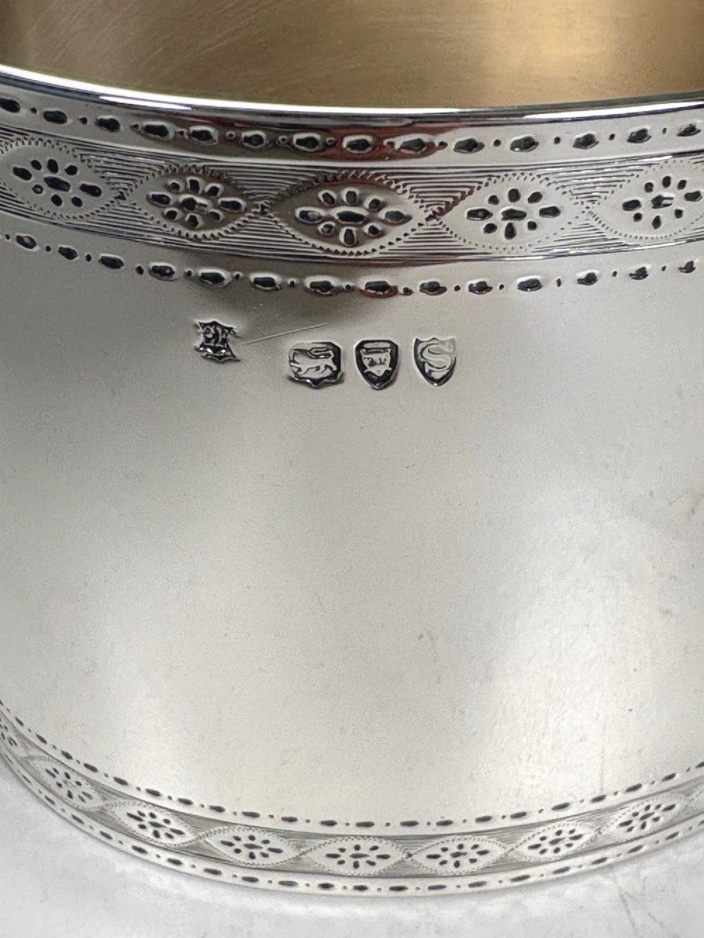 An oval sterling silver tea caddy featuring bright-cut engraved borders, visible hallmarks, and a lid crowned with a sculpted bird finial. View VI