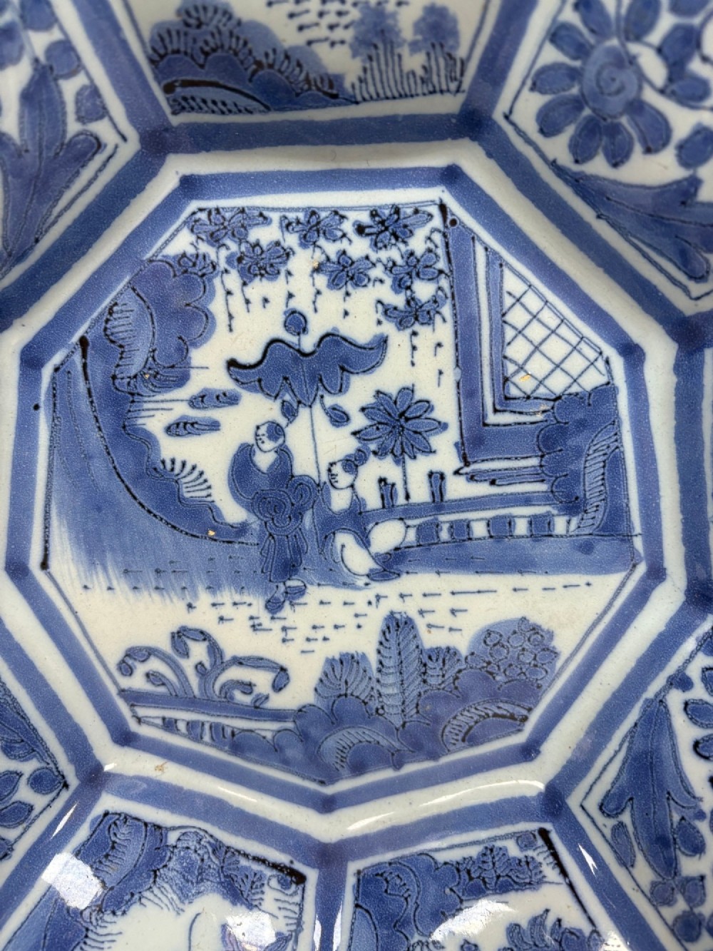 An eighteenth-century lobed tin-glazed earthenware dish featuring cobalt blue hand-painted chinoiserie figures and floral scrollwork within segmented panels. View II