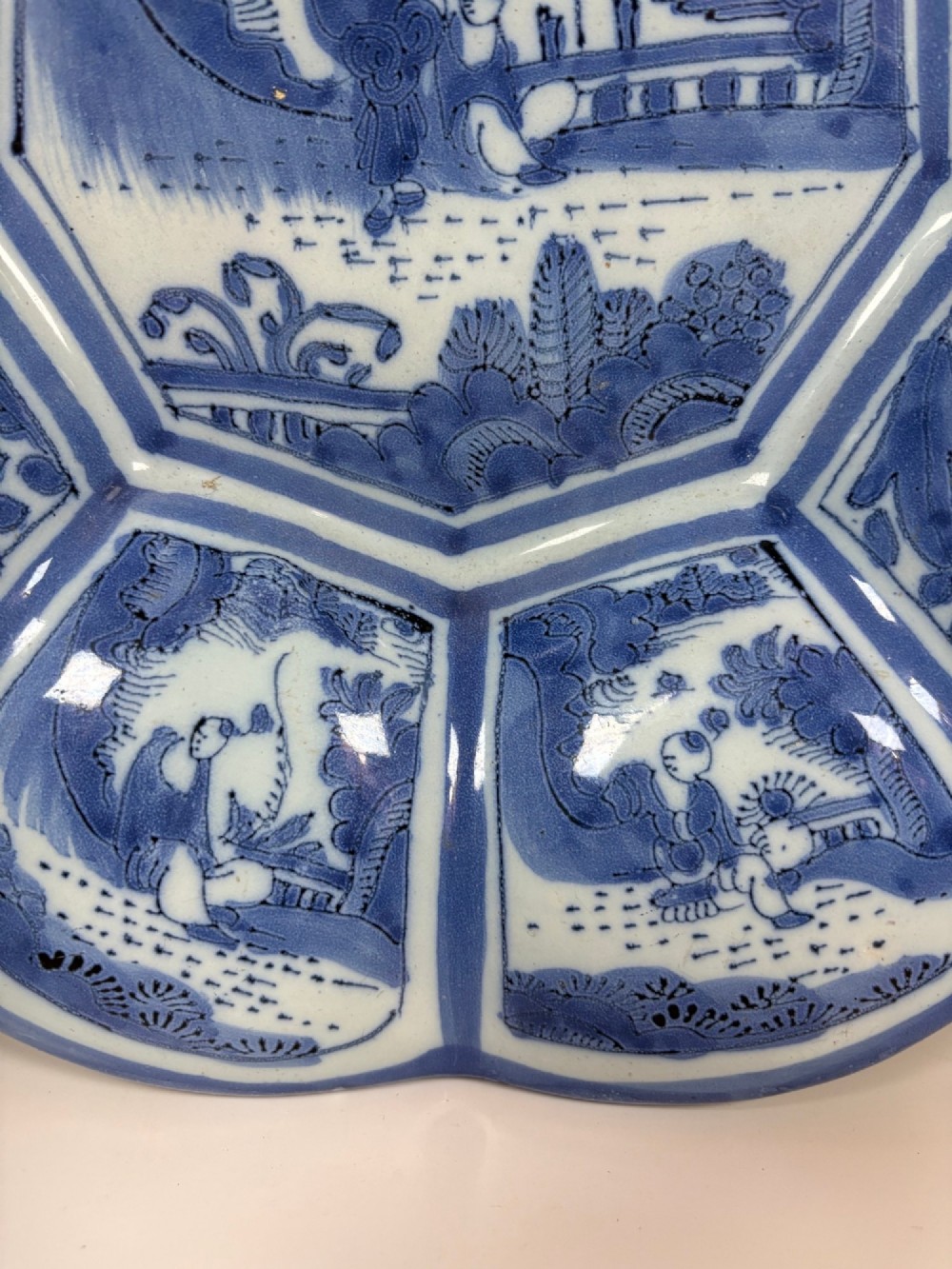 An eighteenth-century lobed tin-glazed earthenware dish featuring cobalt blue hand-painted chinoiserie figures and floral scrollwork within segmented panels. View III