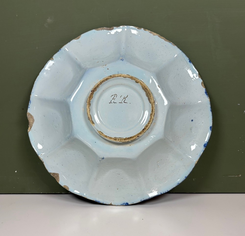 An eighteenth-century lobed tin-glazed earthenware dish featuring cobalt blue hand-painted chinoiserie figures and floral scrollwork within segmented panels. View V