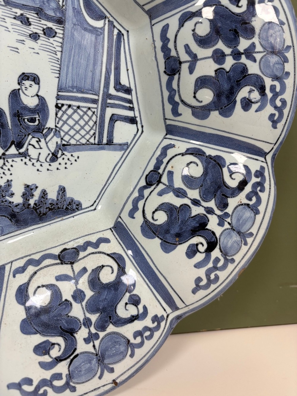 An 18th-century scalloped tin-glazed earthenware dish decorated with hand-painted cobalt blue Chinoiserie figures and floral patterns. View III