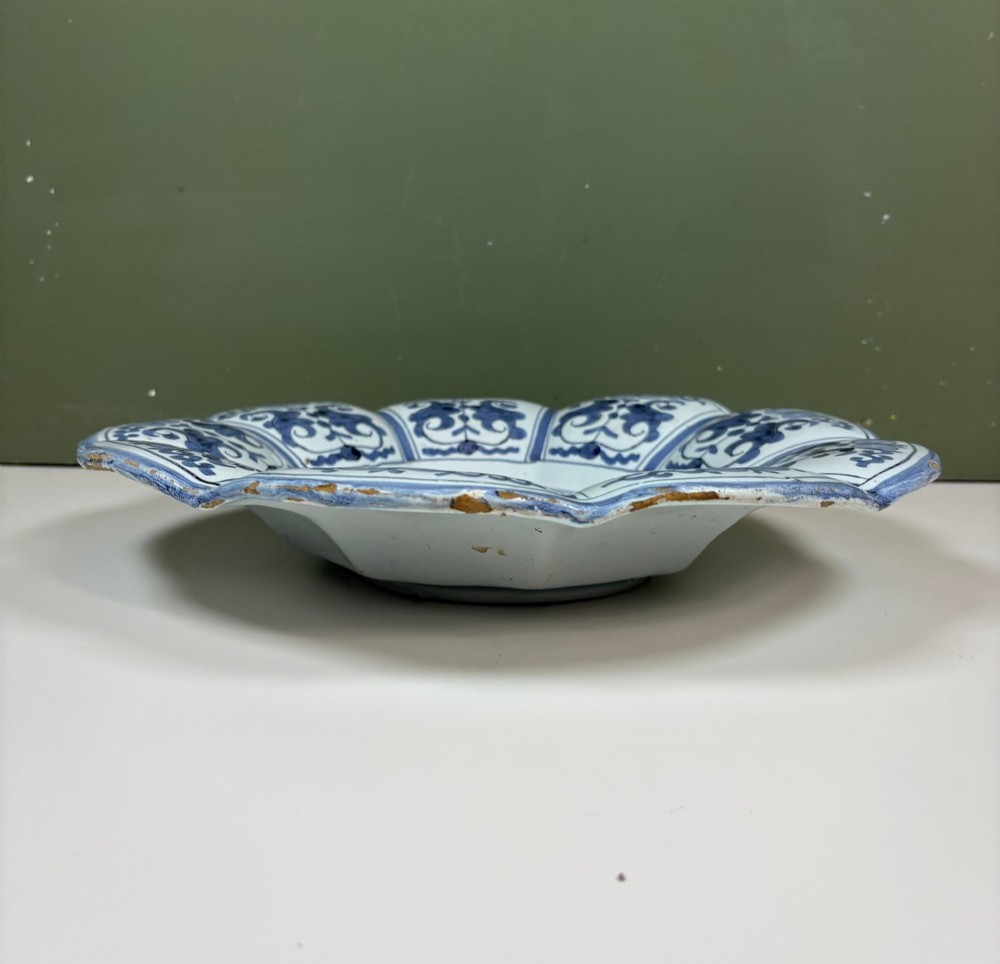 An 18th-century scalloped tin-glazed earthenware dish decorated with hand-painted cobalt blue Chinoiserie figures and floral patterns. View IV