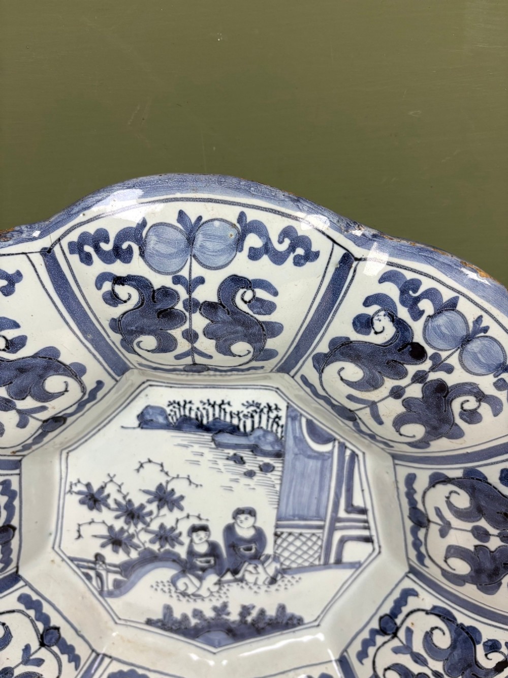 An 18th-century scalloped tin-glazed earthenware dish decorated with hand-painted cobalt blue Chinoiserie figures and floral patterns. View V