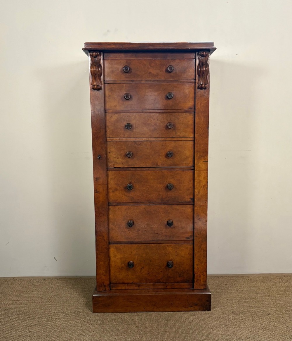 A tall Victorian walnut Wellington chest featuring six drawer fronts, carved corbels, and an open drop-front secretaire revealing internal pigeonholes and small drawers. View II