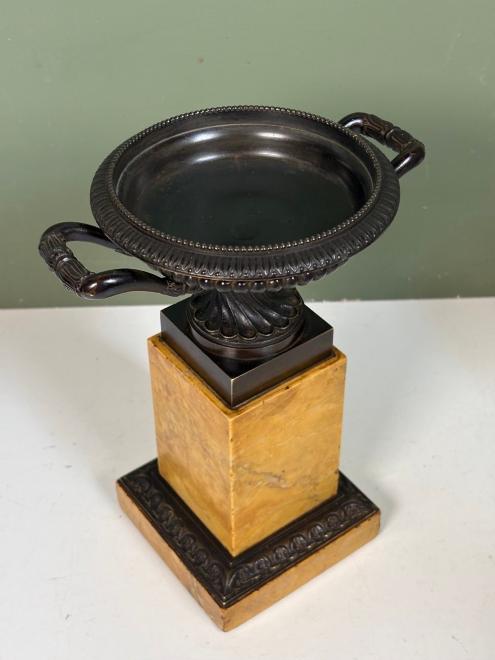 A pair of 19th-century dark patinated bronze tazzas with twin loop handles, elevated on tall yellow marble pedestal bases. View II