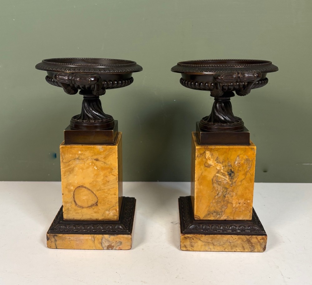 A pair of 19th-century dark patinated bronze tazzas with twin loop handles, elevated on tall yellow marble pedestal bases. View V