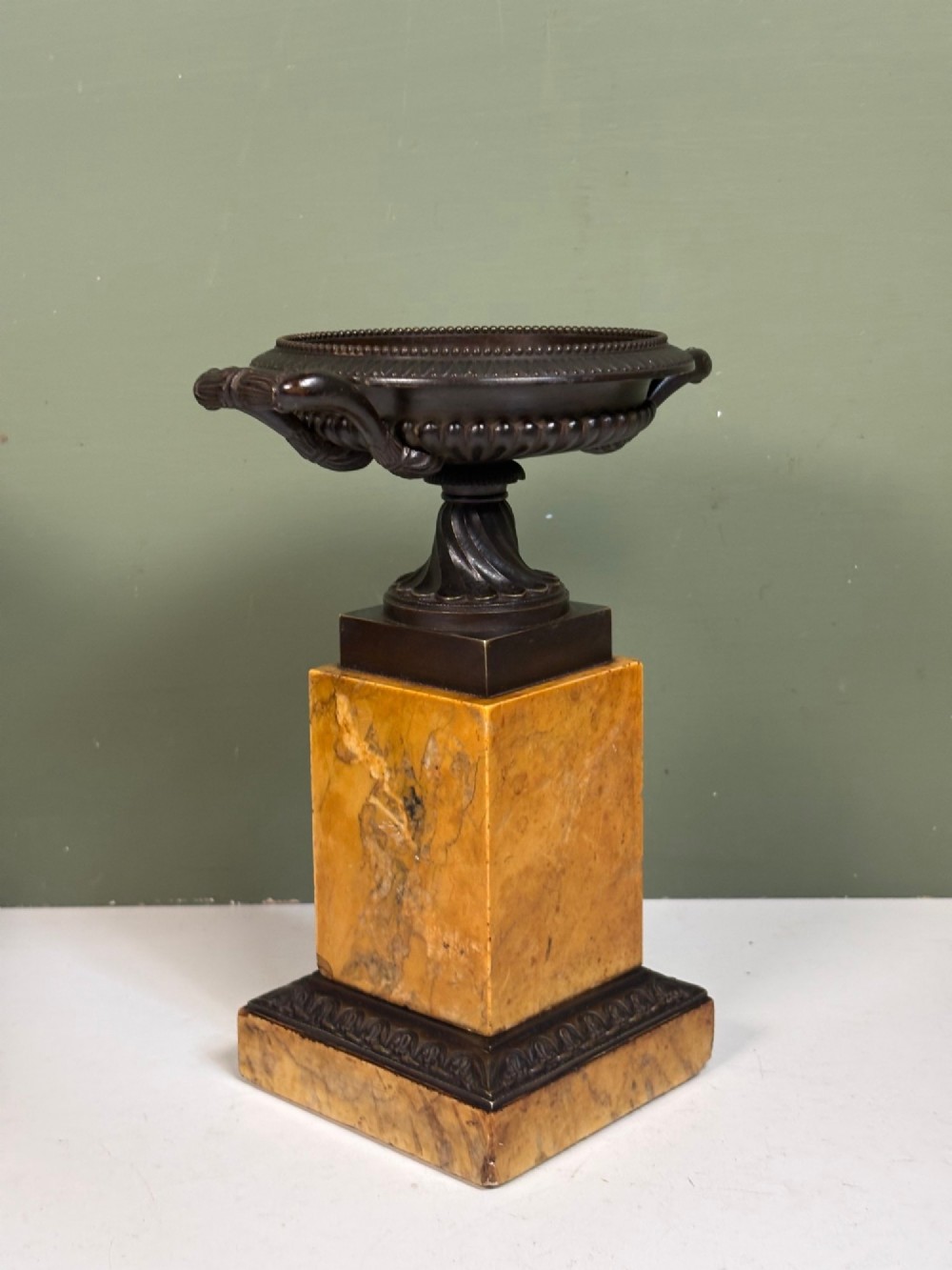 A pair of 19th-century dark patinated bronze tazzas with twin loop handles, elevated on tall yellow marble pedestal bases. View VI