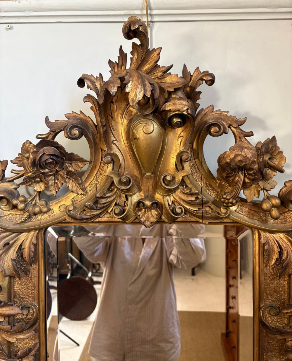 A 19th-century Rococo Revival carved giltwood wall mirror featuring ornate floral cresting, acanthus leaf details, and a central mirror plate. View II