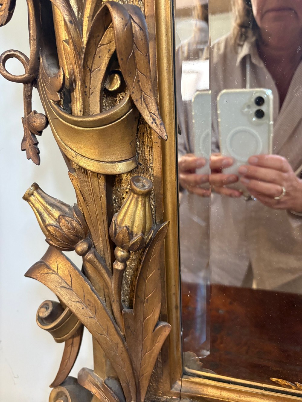 A 19th-century Rococo Revival carved giltwood wall mirror featuring ornate floral cresting, acanthus leaf details, and a central mirror plate. View V