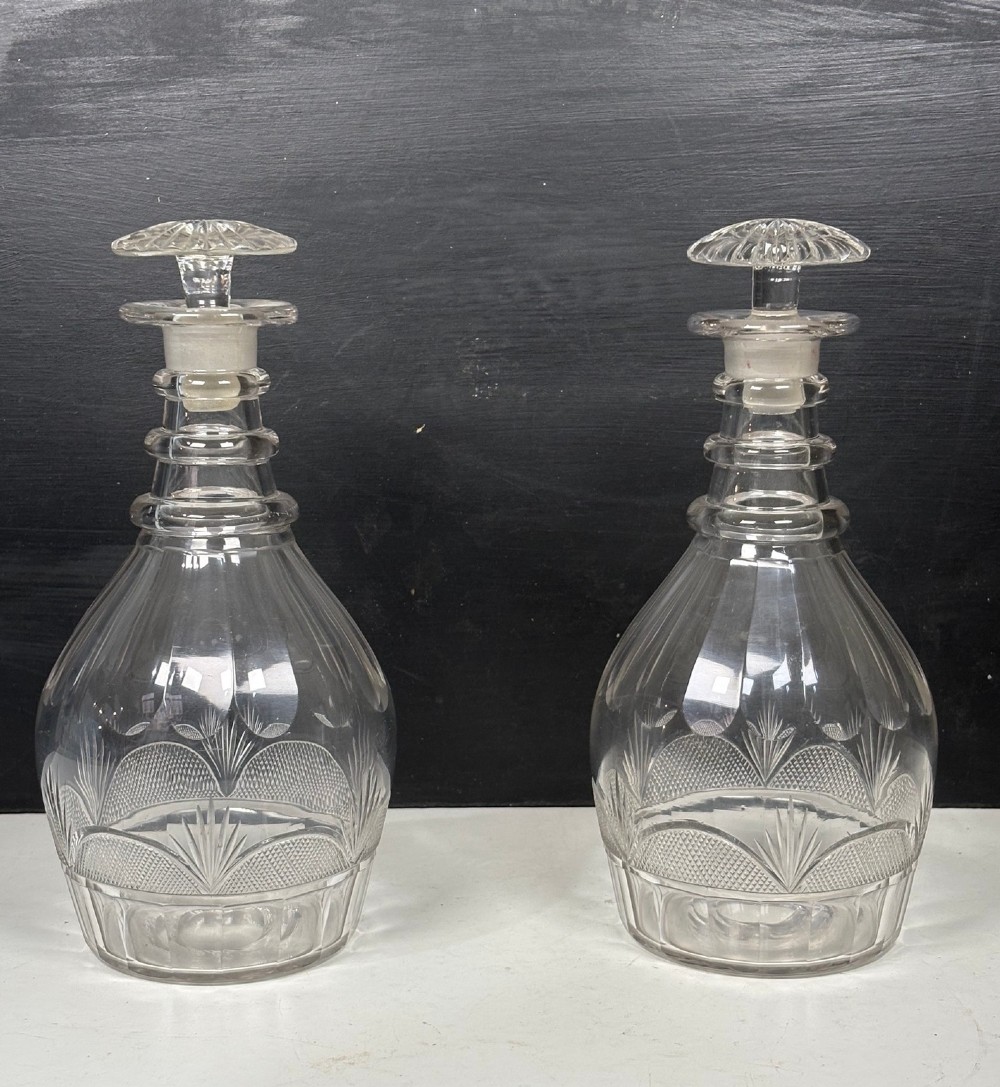 A pair of 19th-century clear cut glass decanters featuring triple neck rings, mushroom stoppers, and wheel-cut geometric panel details. View II