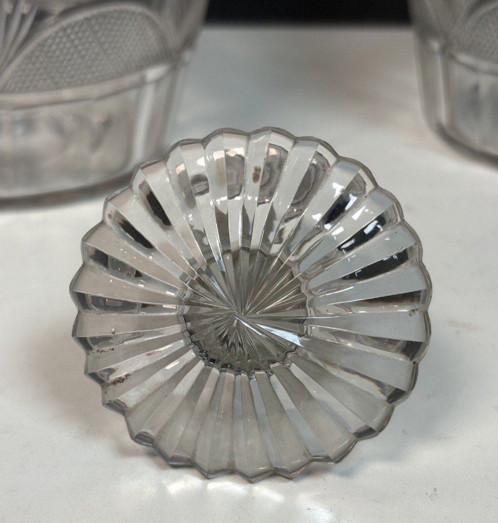 A pair of 19th-century clear cut glass decanters featuring triple neck rings, mushroom stoppers, and wheel-cut geometric panel details. View VI