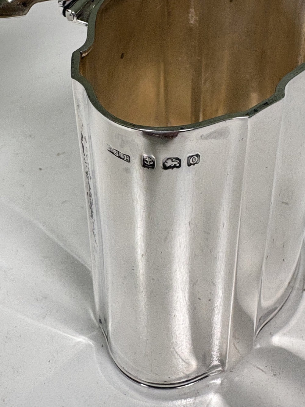 A polished cylindrical solid silver caddy featuring lobed vertical panels, a fitted flush lid, and an ornate scroll finial handle. View VI