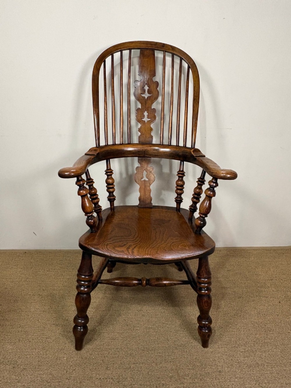 A 19th-century oak and elm Windsor armchair featuring a hoop back with spindles, a central pierced splat, turned arm supports, turned legs, and a saddle seat. View II