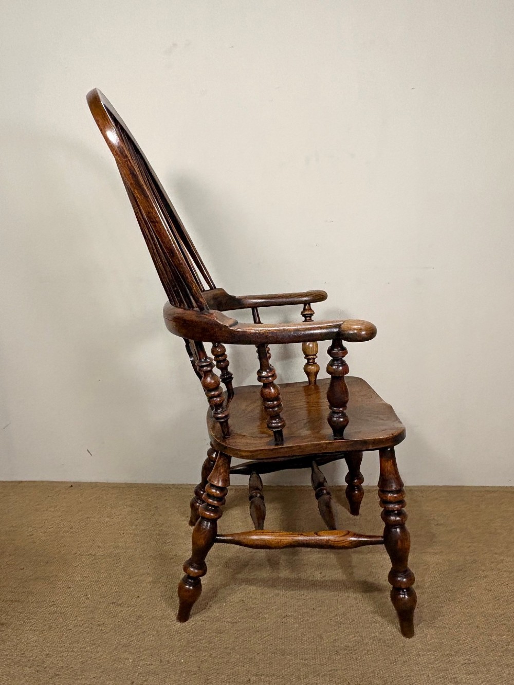 A 19th-century oak and elm Windsor armchair featuring a hoop back with spindles, a central pierced splat, turned arm supports, turned legs, and a saddle seat. View III