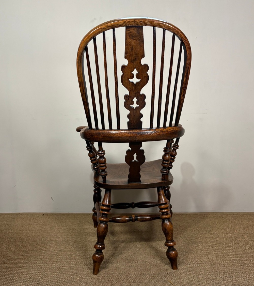 A 19th-century oak and elm Windsor armchair featuring a hoop back with spindles, a central pierced splat, turned arm supports, turned legs, and a saddle seat. View IV
